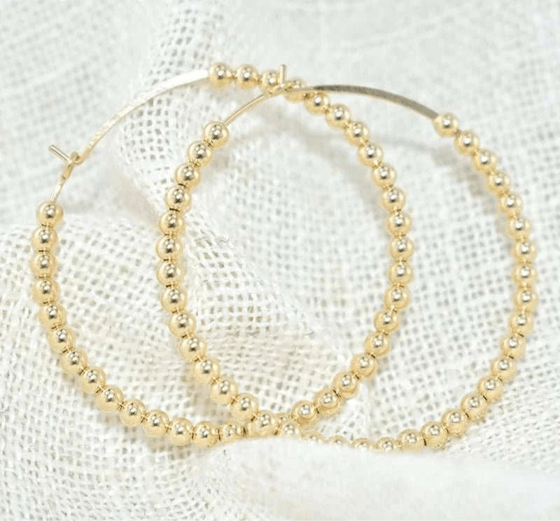 14K gold-filled everyday hoop earrings on fabric background.