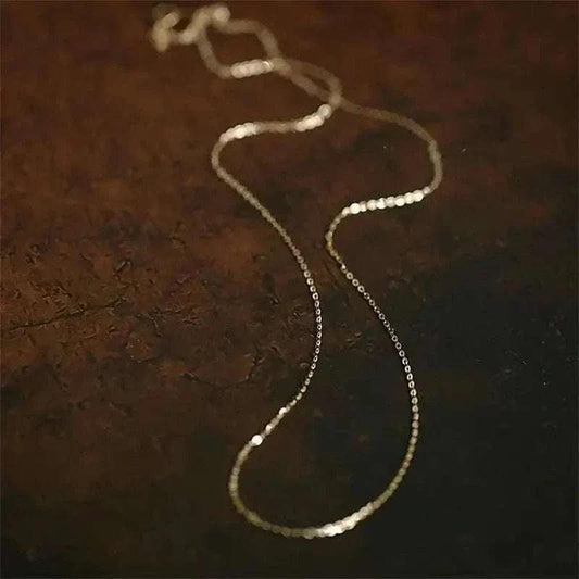14K solid gold minimalist necklace displayed on a dark background, showcasing its elegant and delicate design.