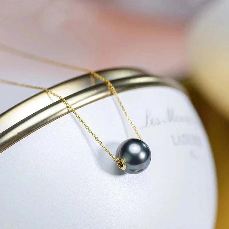 18K gold necklace with Tahitian black pearl pendant on elegant display.