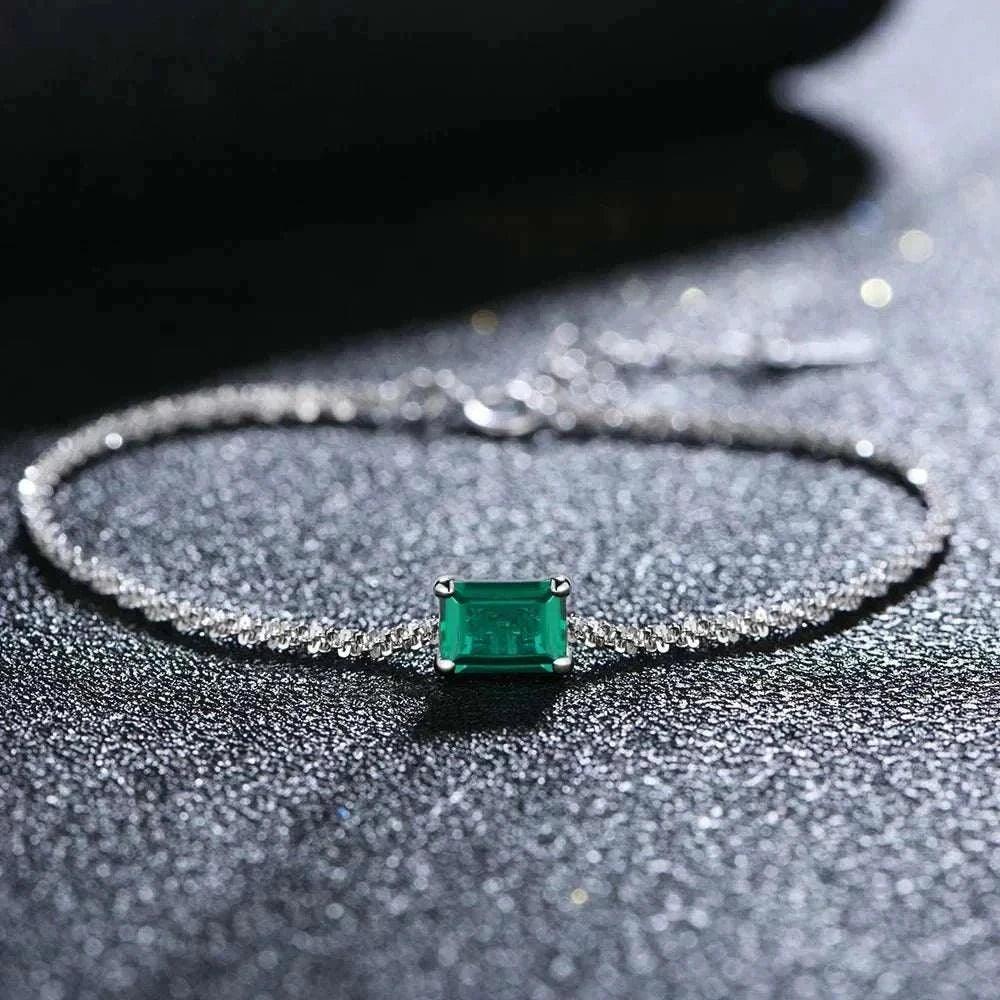 Elegant 925 silver emerald moissanite bangle with radiant gemstones on a dark background.
