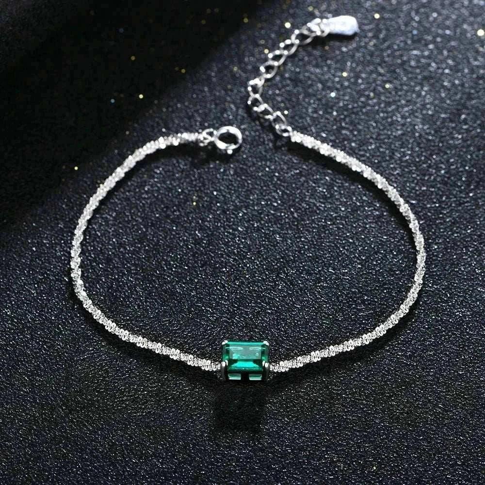 Elegant 925 silver emerald moissanite bangle on dark surface.