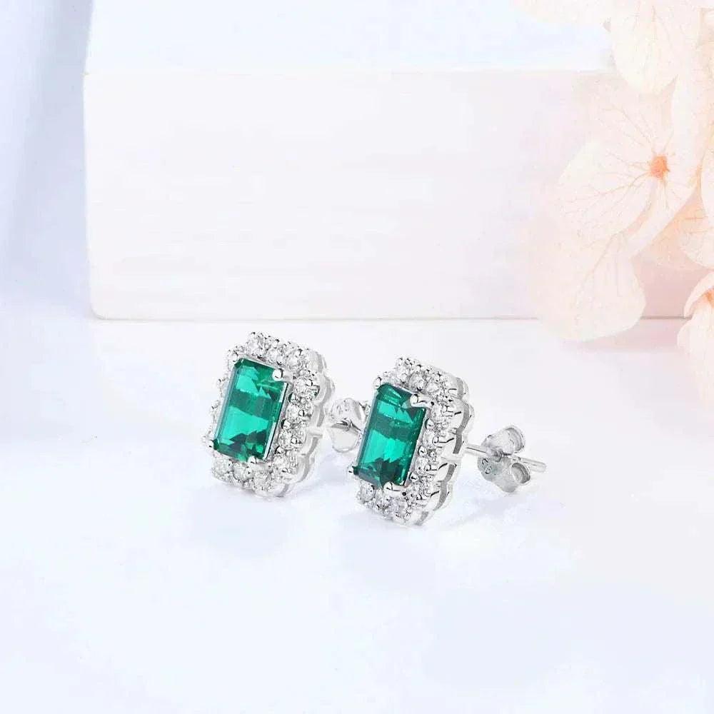 Elegant octagon cut emerald stud earrings on display, featuring vibrant green gemstones set in sterling silver with rhodium plating.