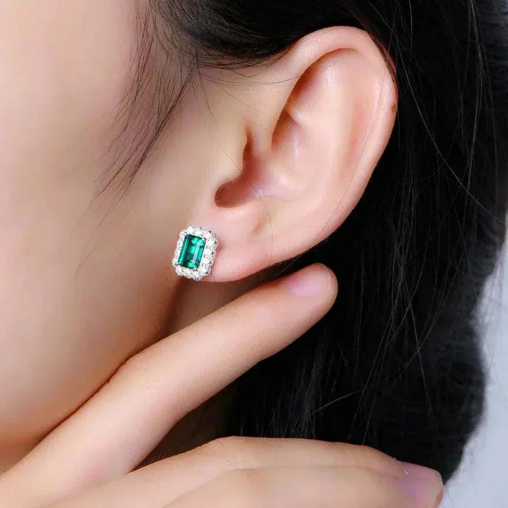 Elegant octagon cut emerald stud earrings on ear.