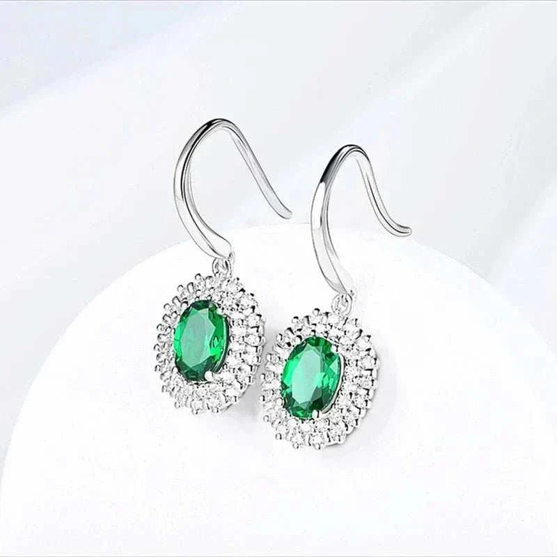 Emerald Moissanite Dangle Earrings in sterling silver with oval VVS1 emeralds.
