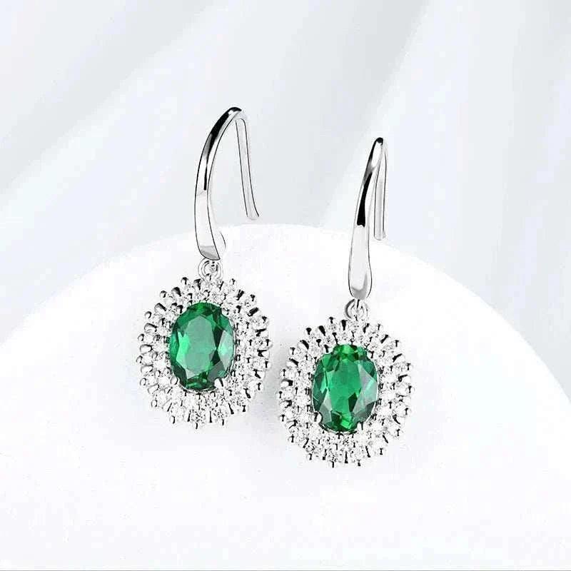 Emerald Moissanite Dangle Earrings in sterling silver showcasing oval green gemstones.