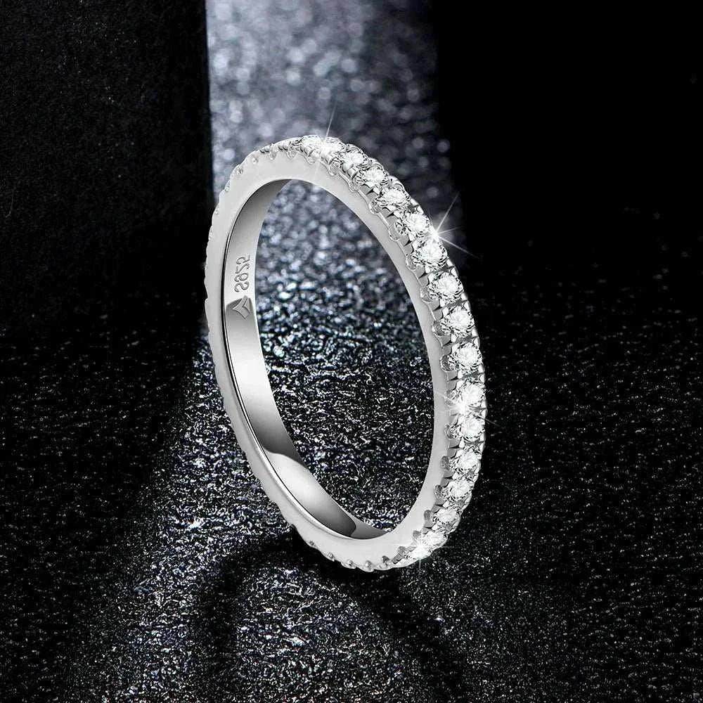 Moissanite full eternity ring in sterling silver with sparkling gemstones on a textured surface.