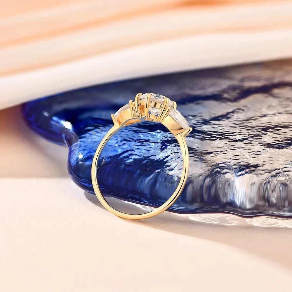 Moissanite Halo Engagement Ring in Yellow Gold on blue textured surface.