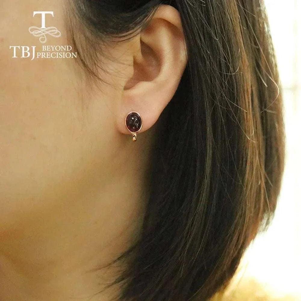 Natural Mozambique garnet silver earrings in rose gold on woman's ear, showcasing 4.6ct oval-cut gemstones.